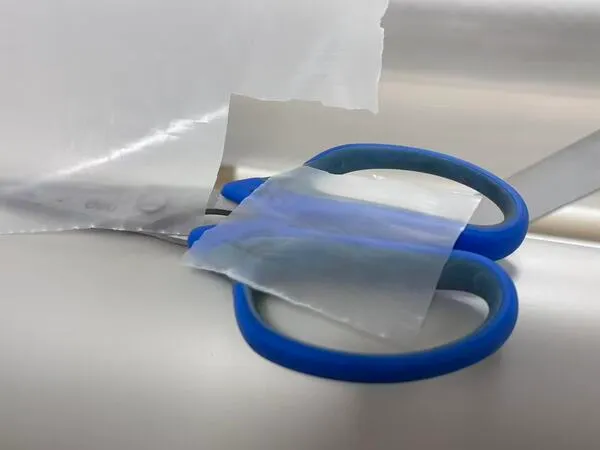 Cutting a small piece of hot-melt adhesive film using blue scissors
