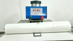 Industrial pneumatic heat press machine with a roll of white hot-melt adhesive film