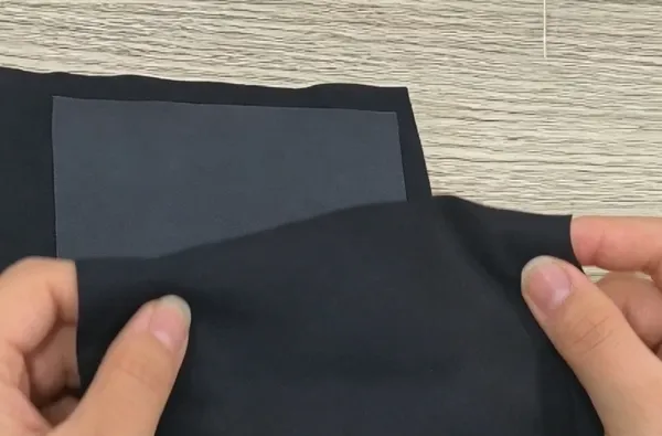 Positioning a layer of hot-melt adhesive film between two black fabric materials