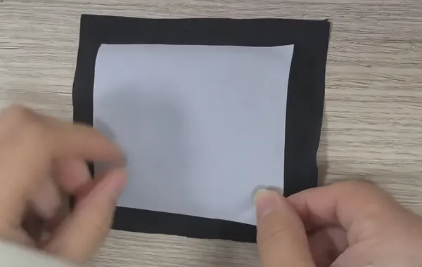 Placing the second layer of black fabric onto the exposed adhesive film