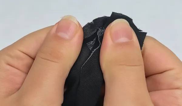 Peeling apart the bonded black fabrics to inspect adhesive penetration